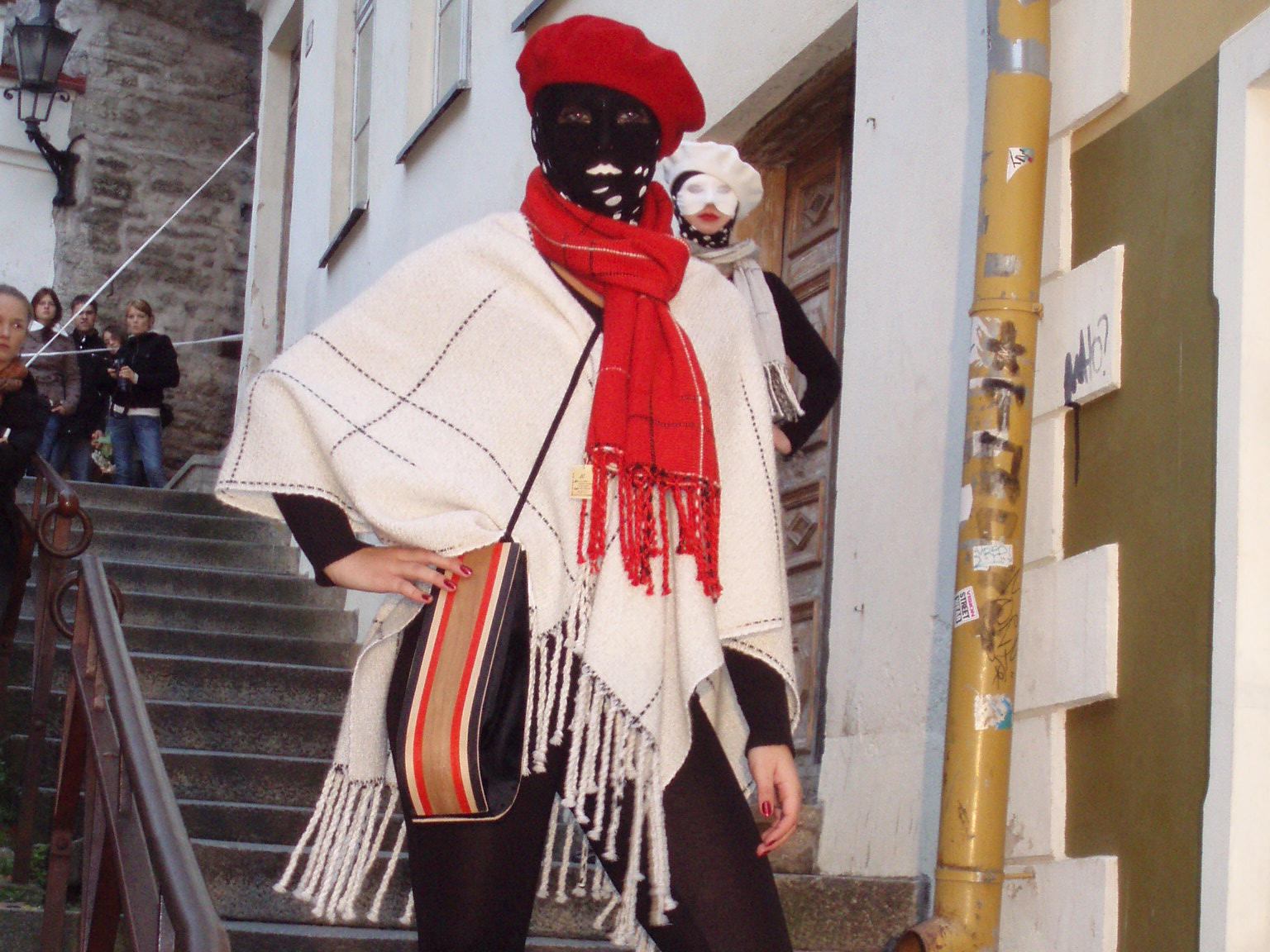model wearing a poncho, beret, balaclava and scarf, with a white-brown-red wooden intarsia bag